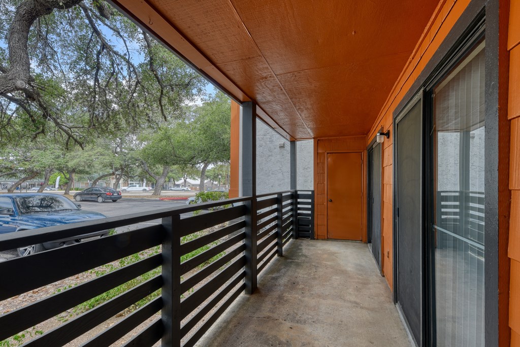 a long balcony with black railing and an orange door