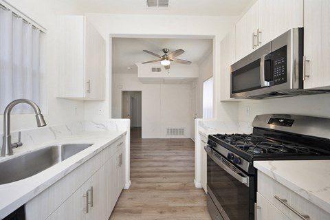 a kitchen with white cabinets and a black stove and a microwave