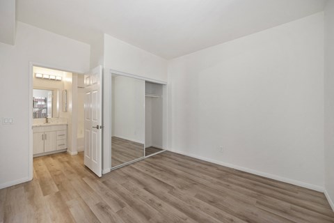 the living room of an apartment with white walls and wood flooring