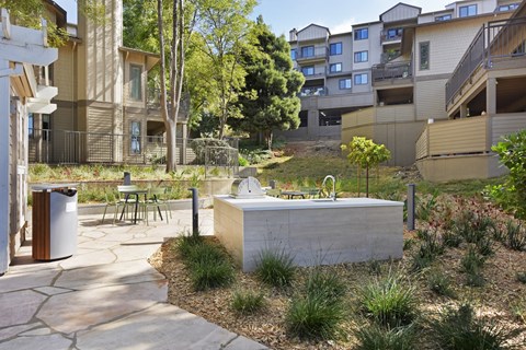 A modern outdoor kitchen area with a sink and a grill.