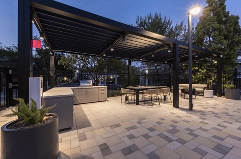 A patio area with a table and chairs under a roof.