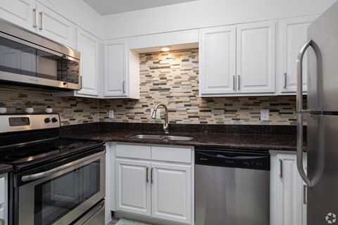A kitchen with white cabinets and a black dishwasher.