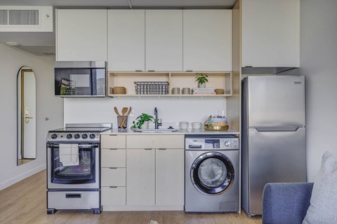 a white kitchen with a washing machine and a stainless steel refrigerator