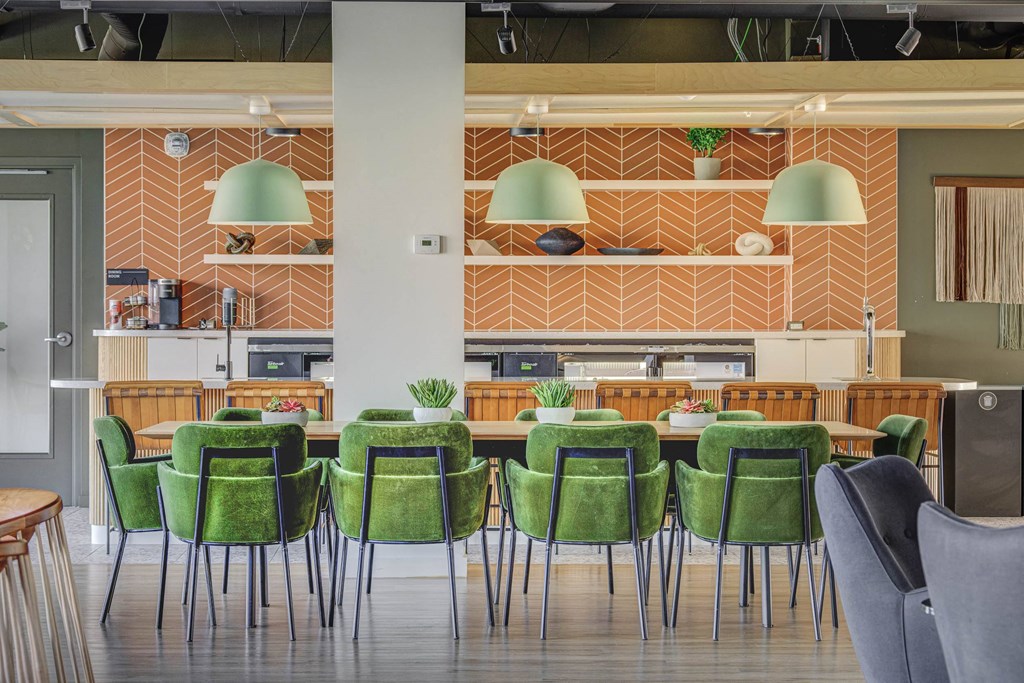 a large table with green chairs and a kitchen in the background
