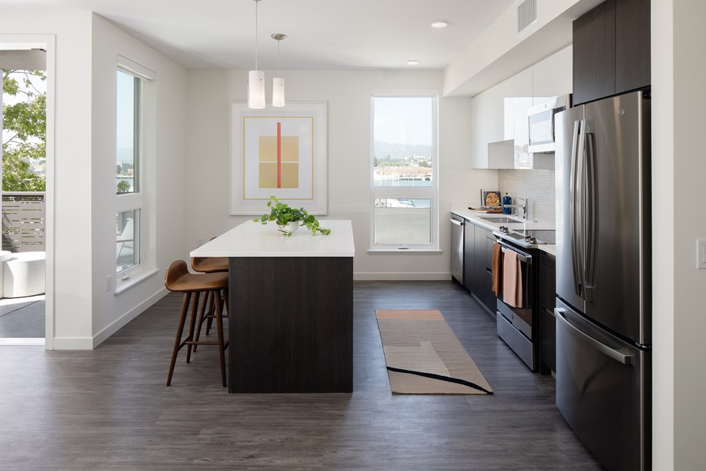 A modern kitchen with a black refrigerator and a bar stool.