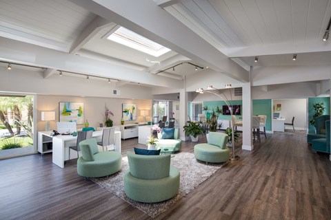 A spacious room with green chairs and wooden floors.