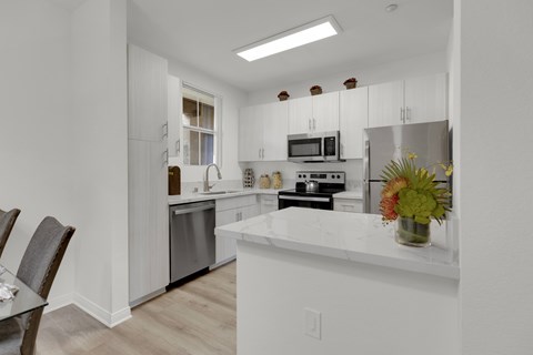 A kitchen with white cabinets and a white counter top.