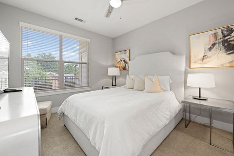 A bedroom with a large bed, a window with blinds, and a ceiling fan.