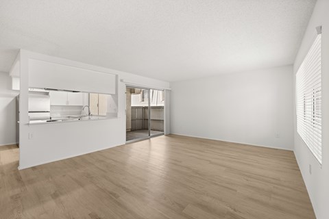 A spacious room with wooden flooring and white walls.