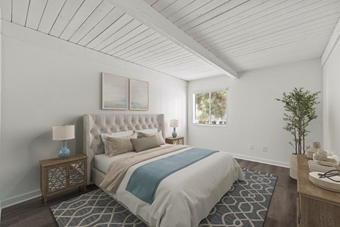 A bedroom with a large bed and a small table with a lamp on it.