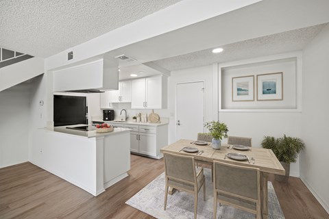 A modern kitchen with a dining table set for two.