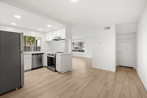 A modern kitchen with wooden floors and white walls.