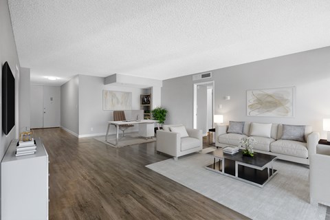 A modern living room with a white sofa set and a wooden floor.