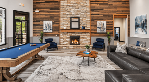 A pool table is in the middle of a room with a fireplace and a couch.