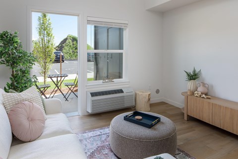 A living room with a white couch and a grey ottoman.