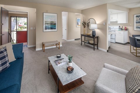 A living room with a blue couch and a coffee table with a vase of flowers on it.