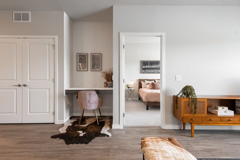 A room with a pink chair and a cowhide rug.