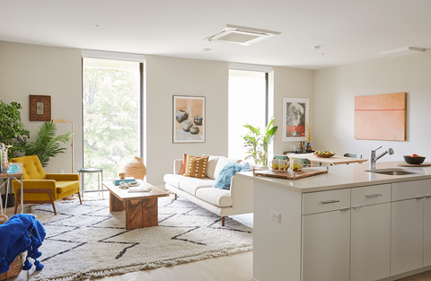 A modern kitchen and living room with a yellow chair and a white couch.