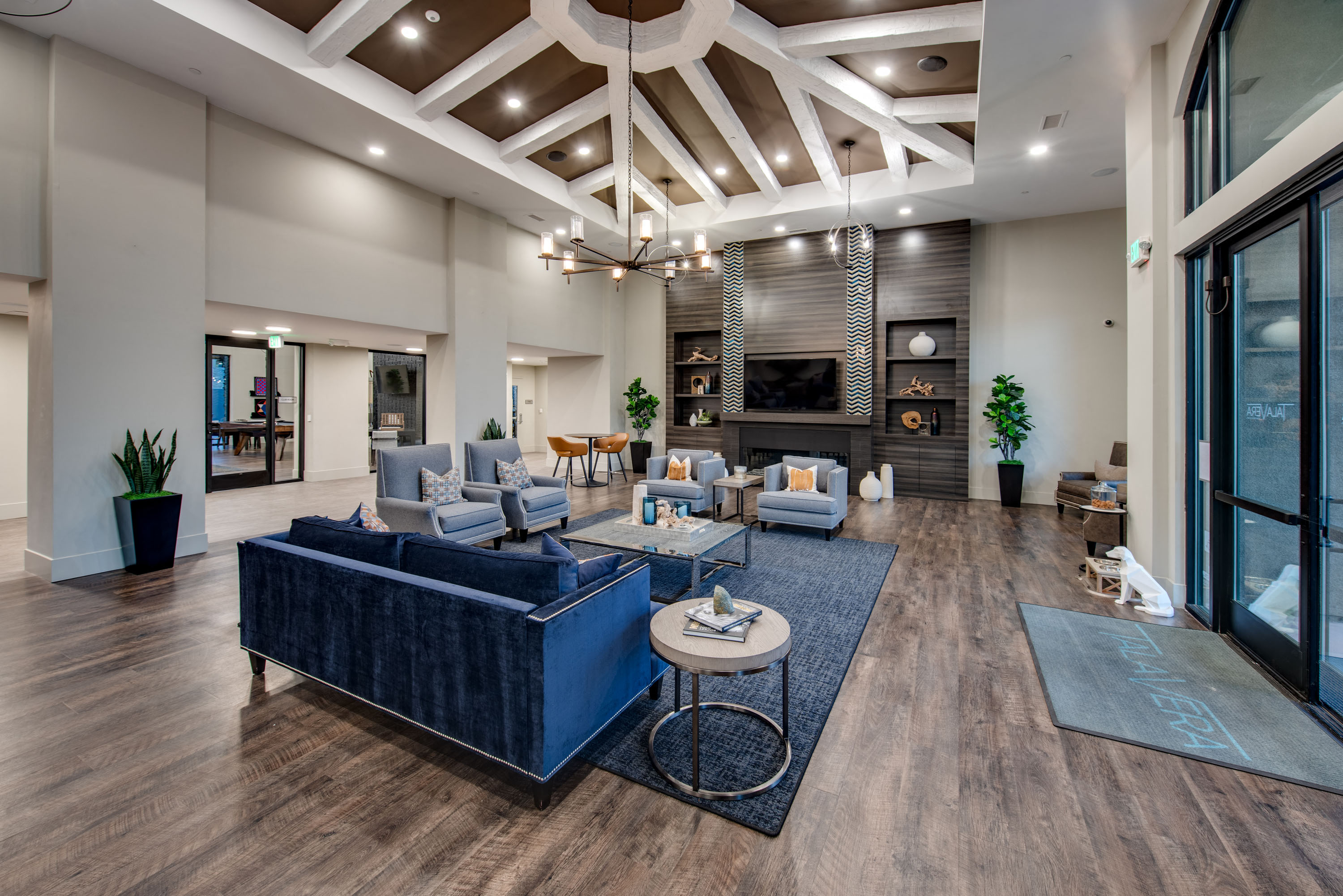 A spacious living room with a blue sofa and wooden floors.