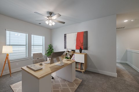 an office with a desk and a ceiling fan