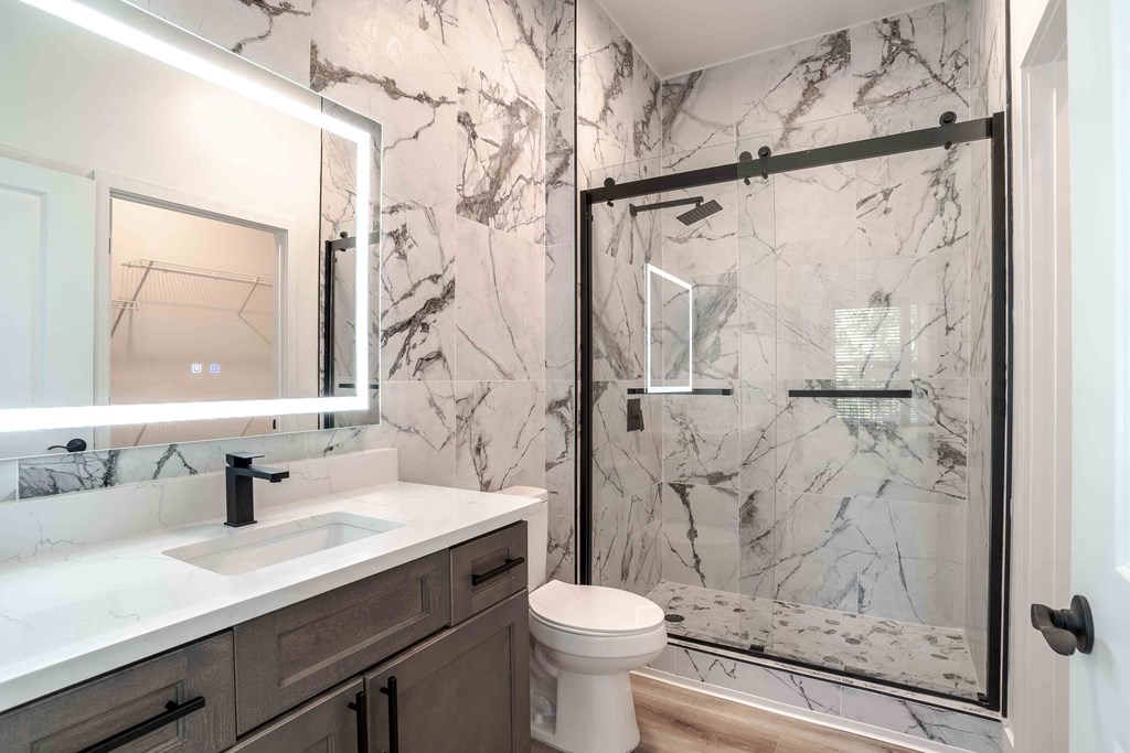A bathroom with a marble wallpaper and a walk-in shower.