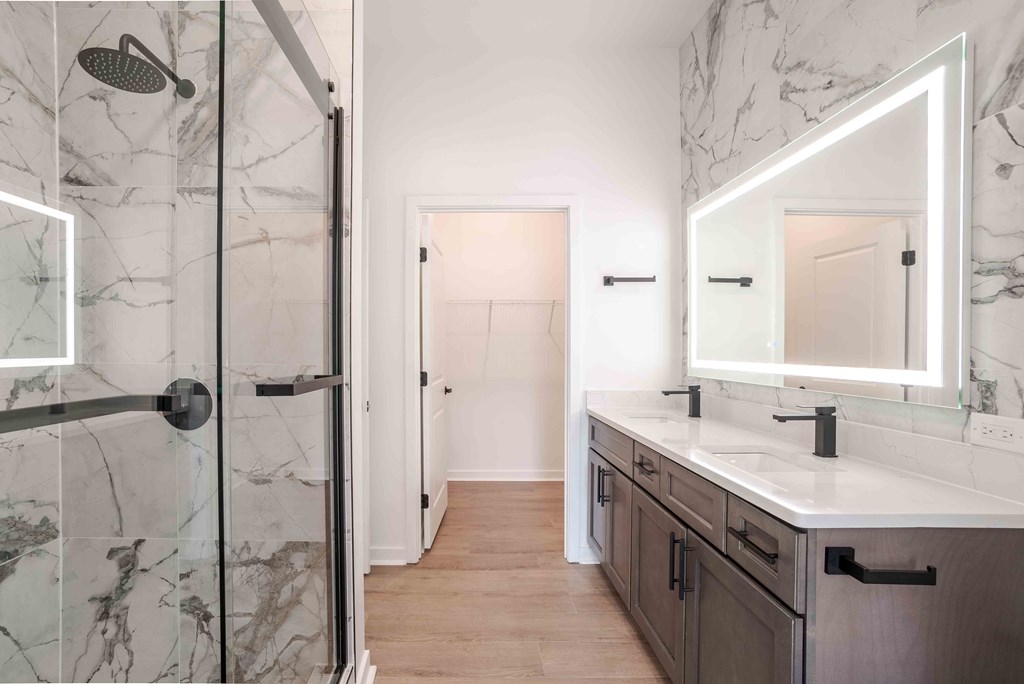 A bathroom with a marble shower and a white sink vanity.