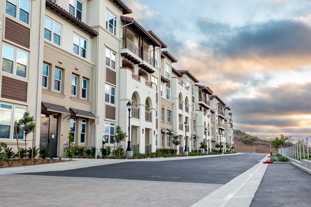 A row of modern apartment buildings with a street in front.