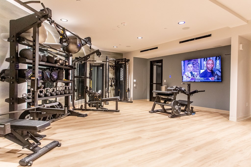 A well equipped gym with a television screen on the wall.