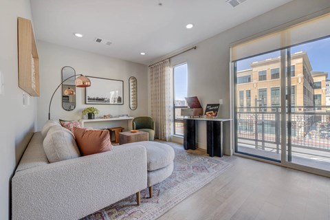 A living room with a grey couch and a large window.