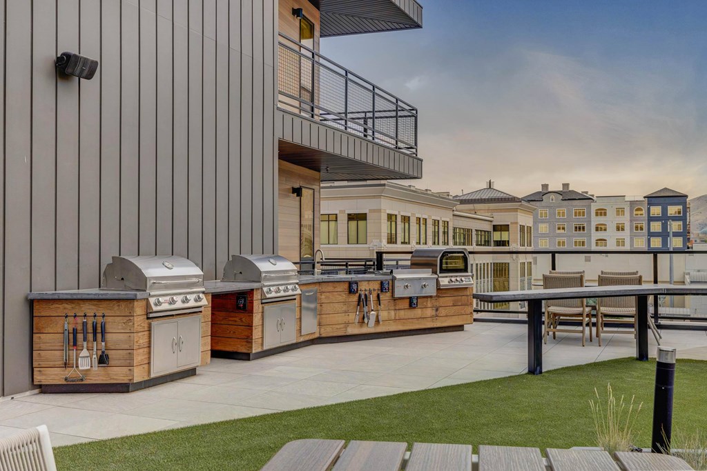 A modern outdoor kitchen area with grills and a dining table.