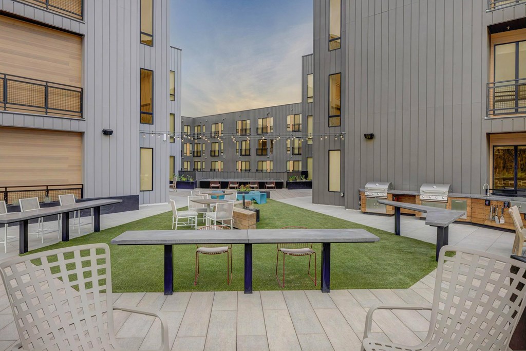 A modern outdoor seating area with white chairs and tables is set up in front of a building.