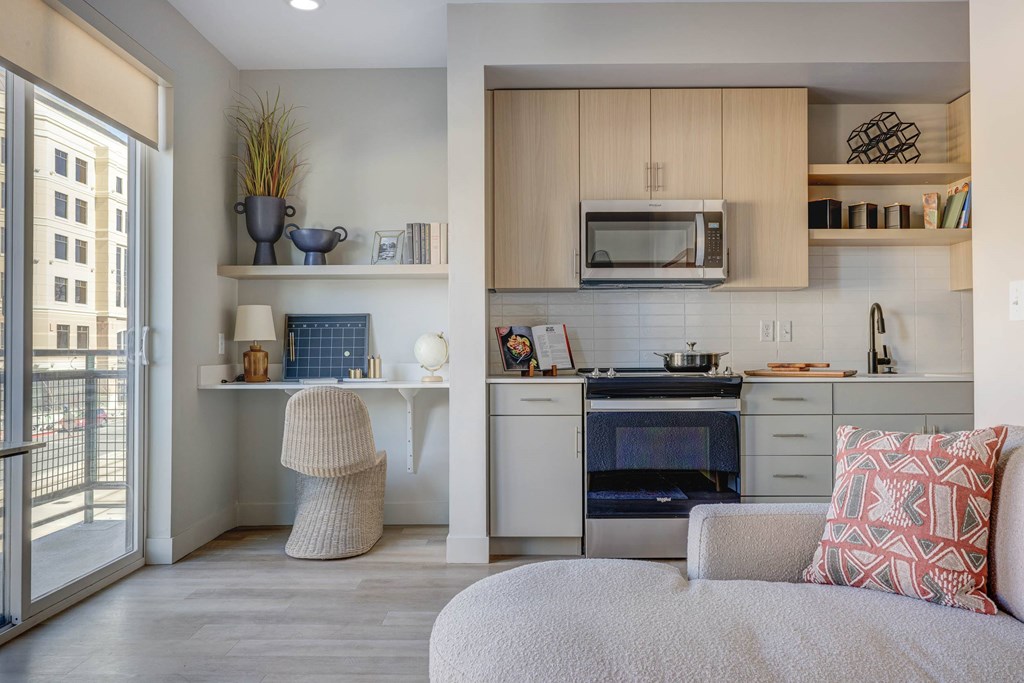 A modern kitchen with a white countertop and a grey couch.