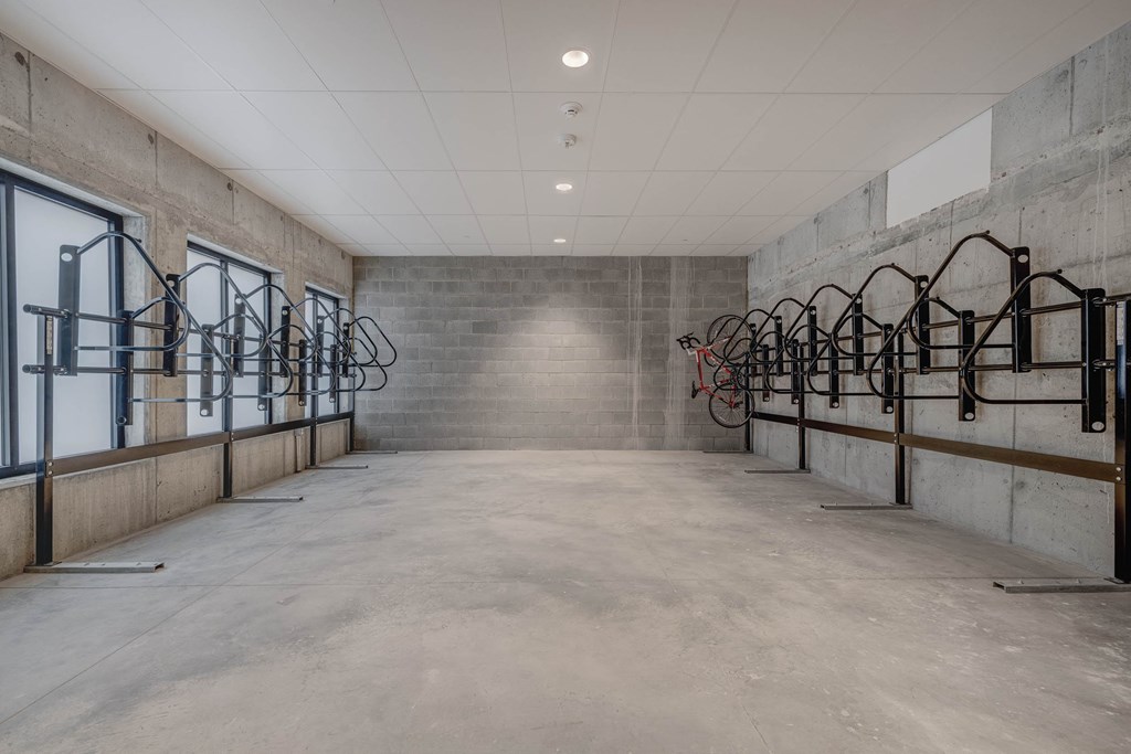A spacious room with a concrete floor and walls, equipped with exercise bikes and mirrors.