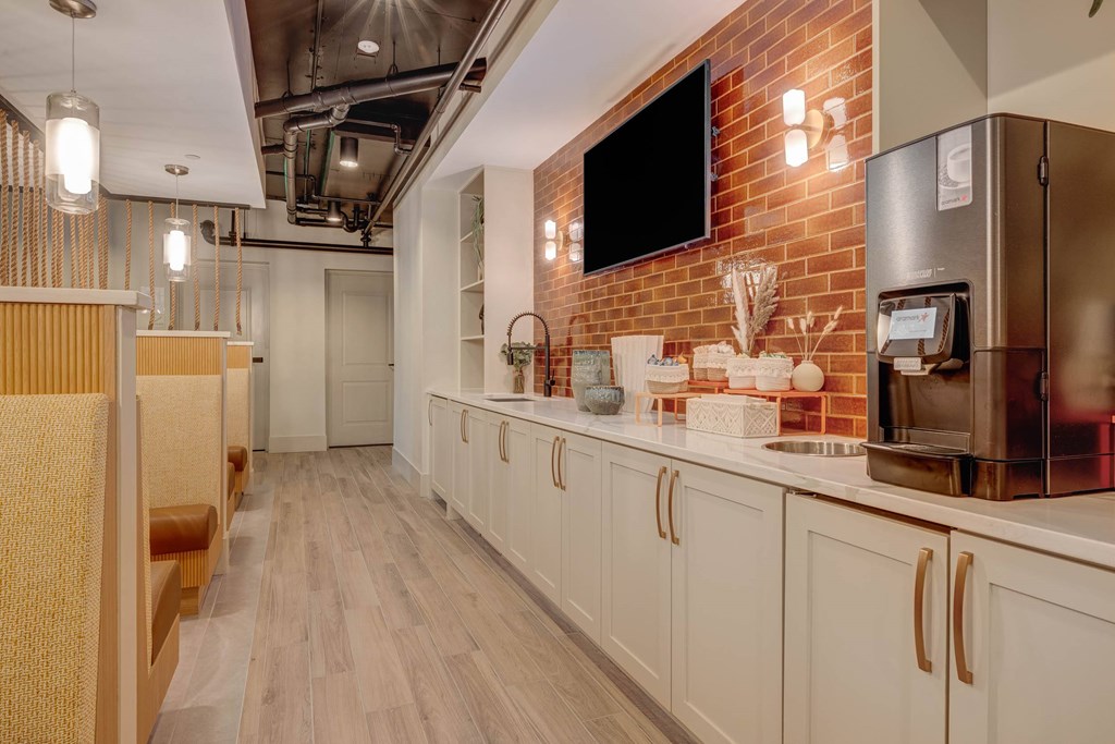 A modern kitchen with white cabinets and a brick wall.