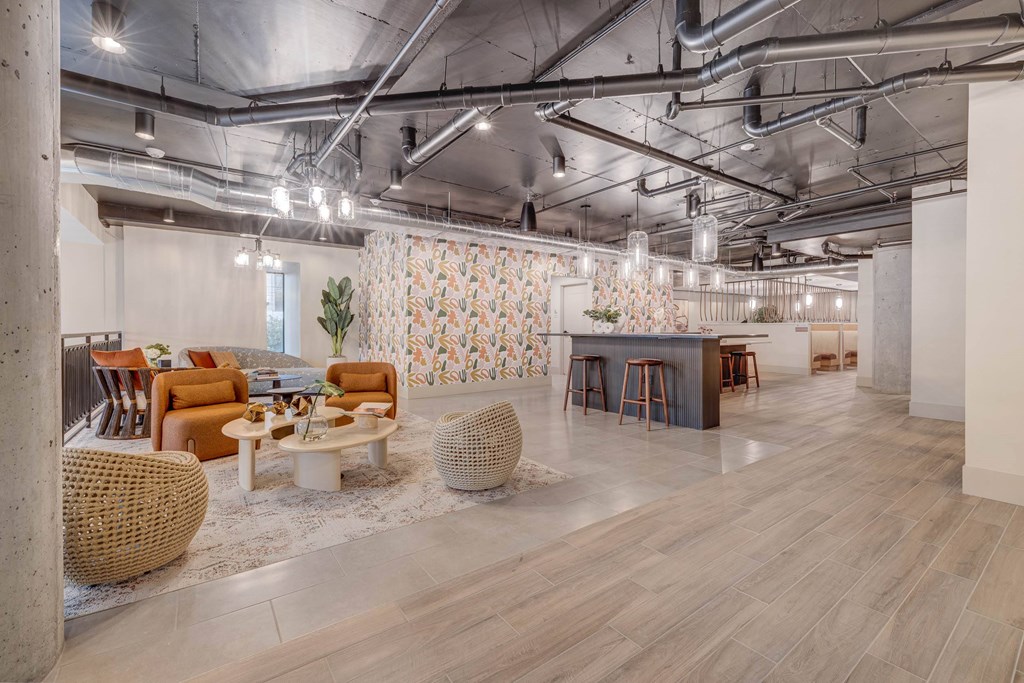 A modern office space with a patterned wallpaper and a mix of wooden and wicker furniture.
