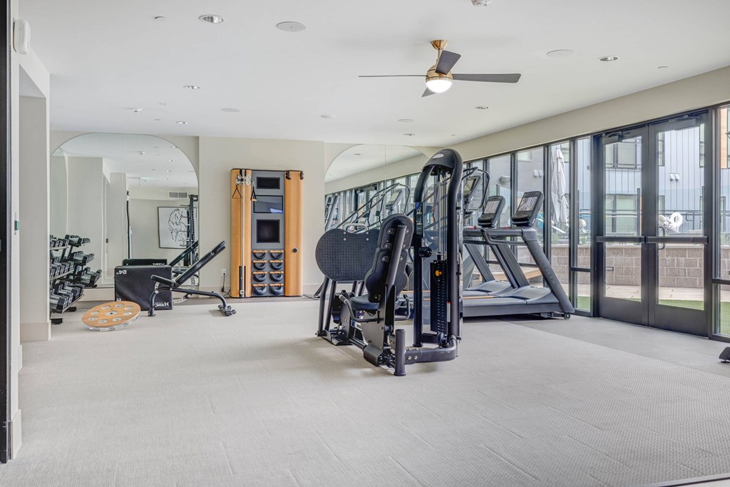 A spacious gym with a variety of equipment including treadmills, elliptical machines, and a weight rack.
