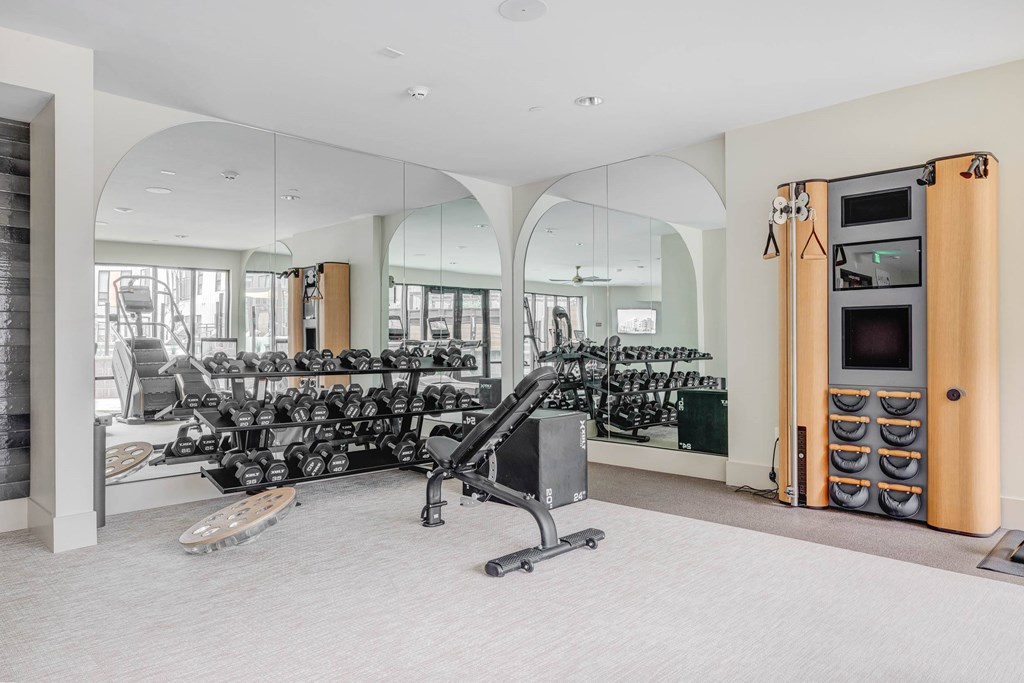 A gym with a variety of equipment including weights and a treadmill.