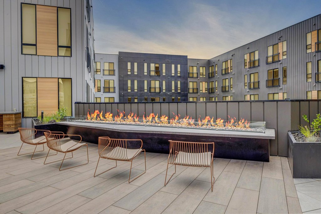A modern outdoor seating area with a fire pit and chairs.