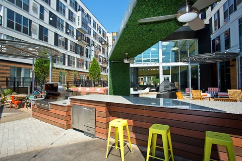 A patio with a bar and green stools.