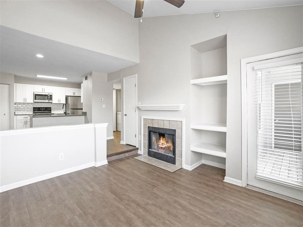a living room with a fireplace and a kitchen in the background