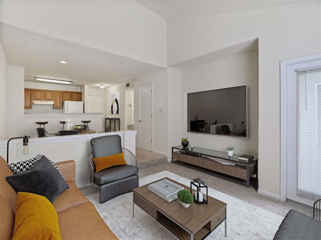 Classic kitchen in background of a living room with a couch and a coffee table in front of a tv