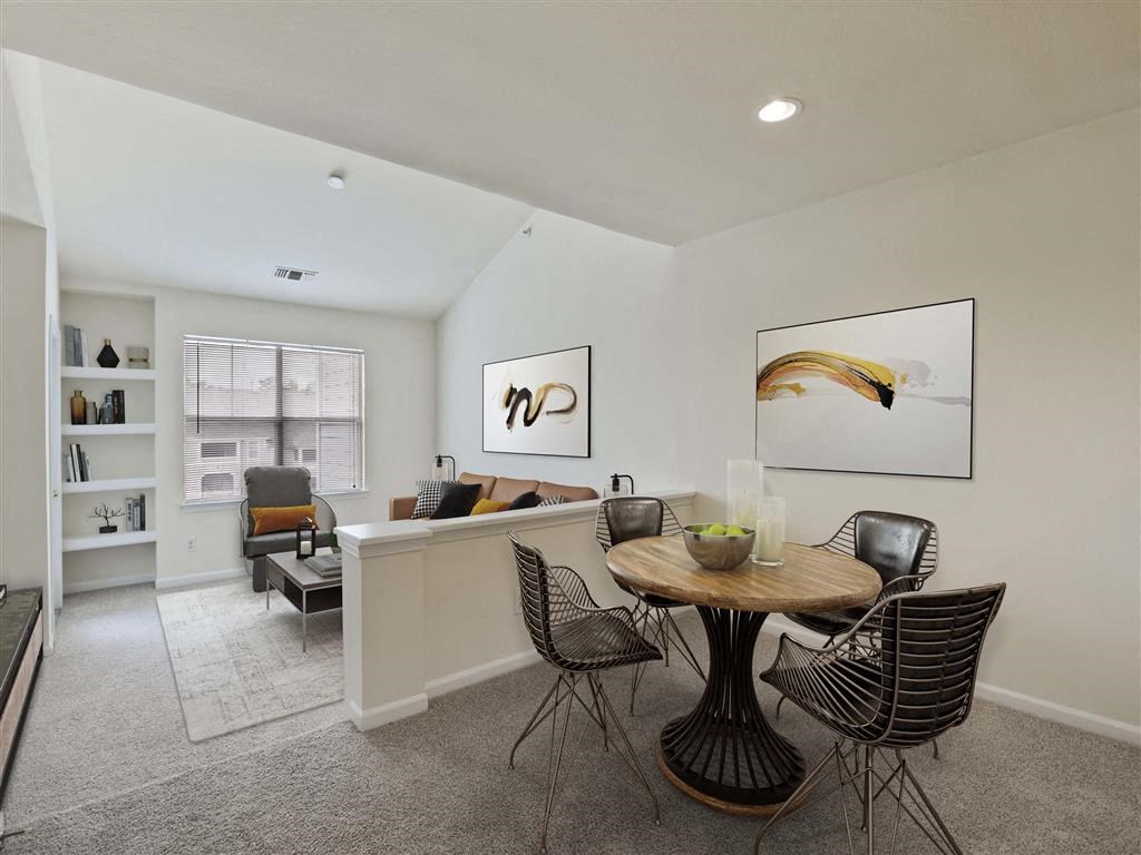 a dining area with a table and chairs and a living room in the background