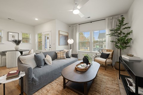 A living room with a grey couch, a coffee table, and a piano.