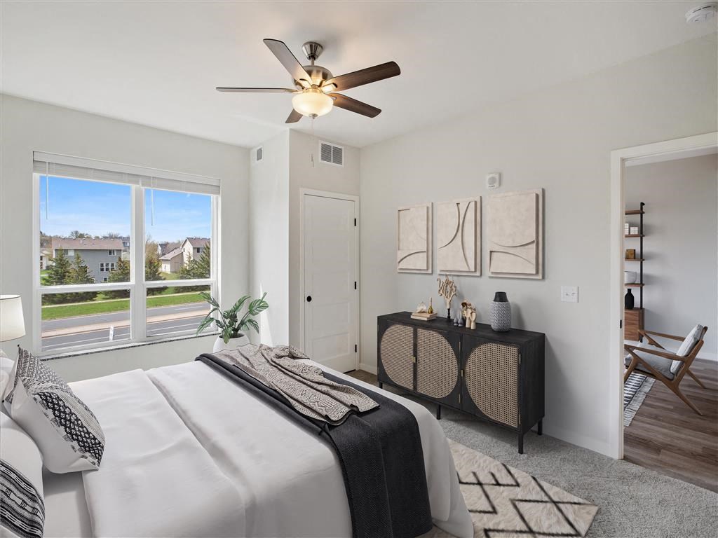 a bedroom with a large window and a ceiling fan