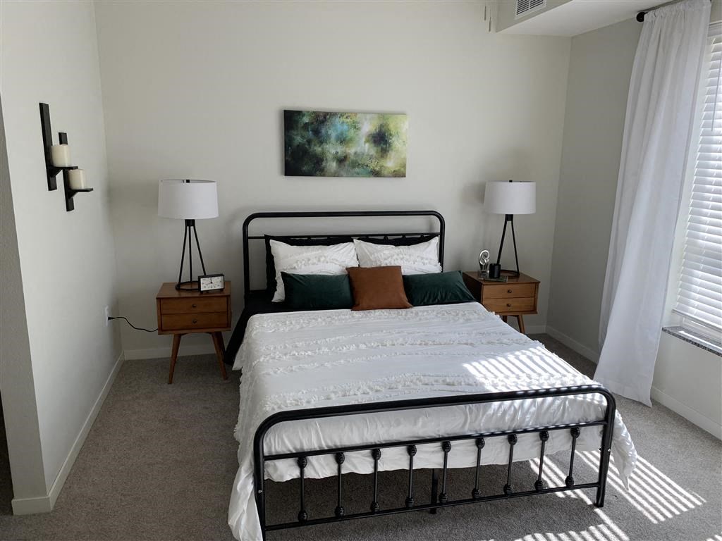 a bedroom with a bed and two lamps and a window