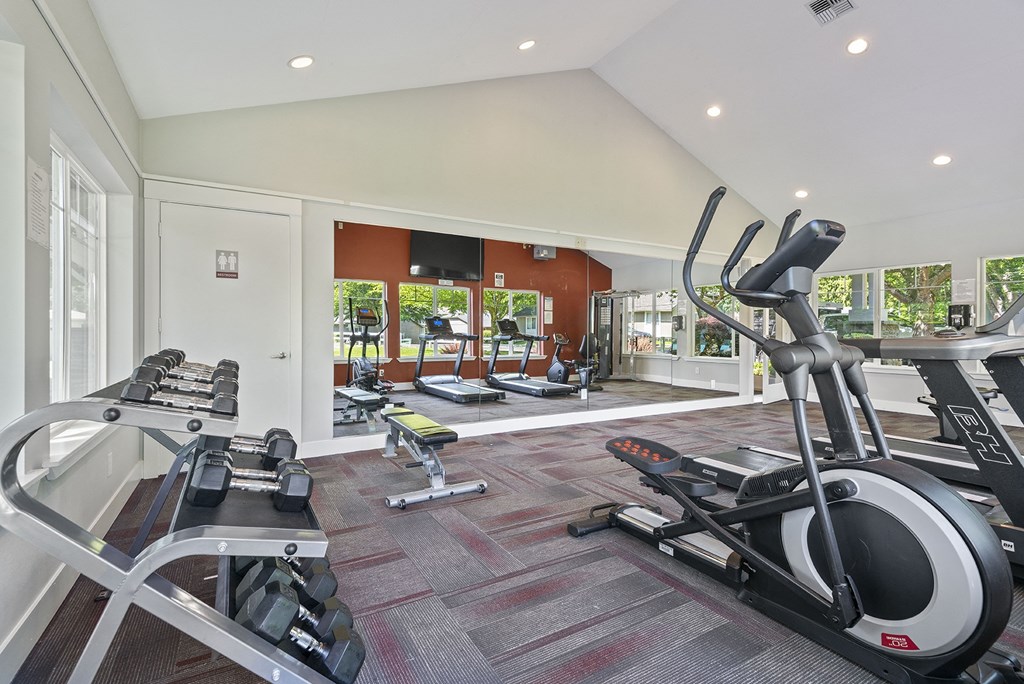 a gym with treadmills and other exercise equipment in a room with windows