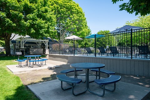 a patio with tables and chairs next to a swimming pool