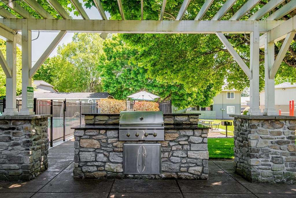 an outdoor kitchen with a grill under a pavilion