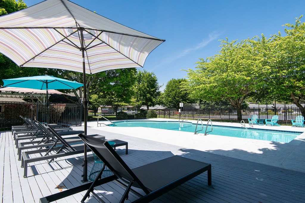 a swimming pool with chairs and an umbrella next to it