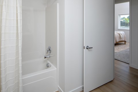 A white bathroom with a tub and a door.